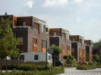 Geschakelde woningen met opvallende geveldelen gecombineerd met een donkerbruine baksteen.